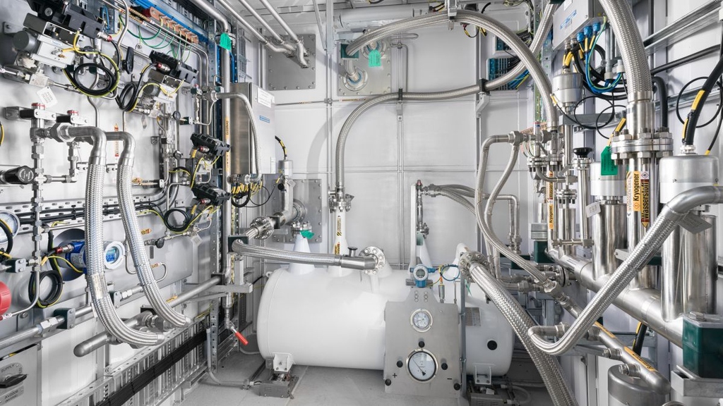 Der Verflüssiger kühlt Wasserstoff-Gas auf kryogene Temperaturen (<20 K). Die so gewonnene Flüssigkeit ermöglicht Synergien mit supraleitenden Bauteilen.