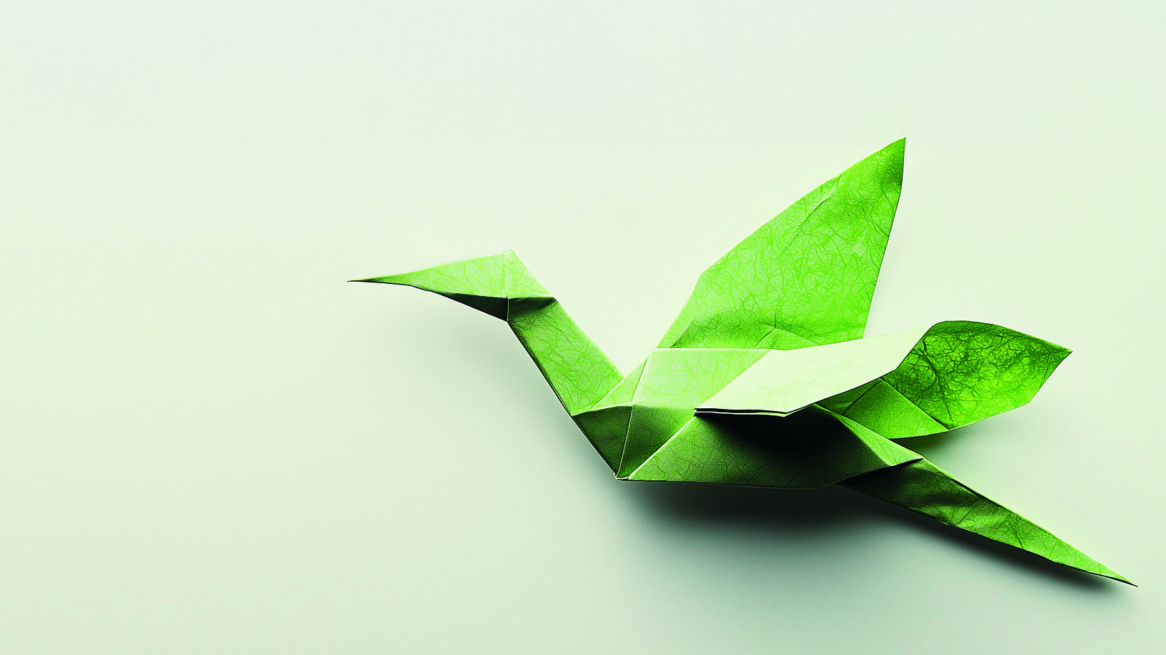AdobeStock Grüner Origami-Kranich auf hellem Hintergrund.
