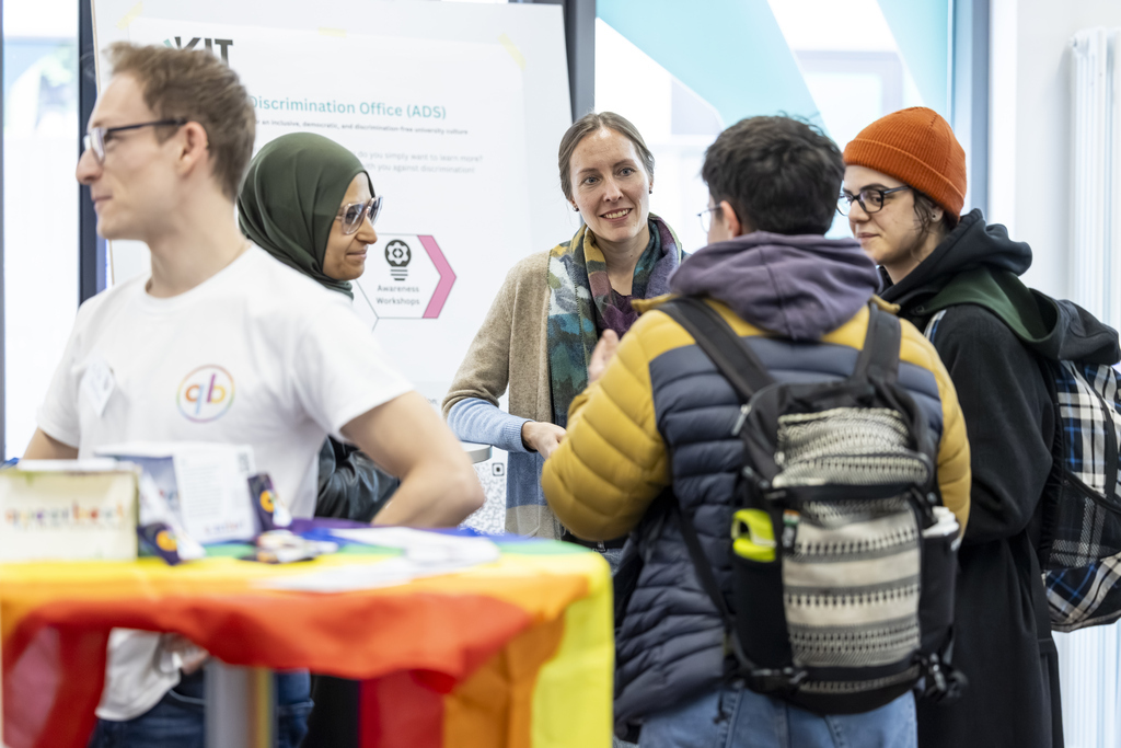 Gruppe von Studierenden im Gespräch vor einem Infostand