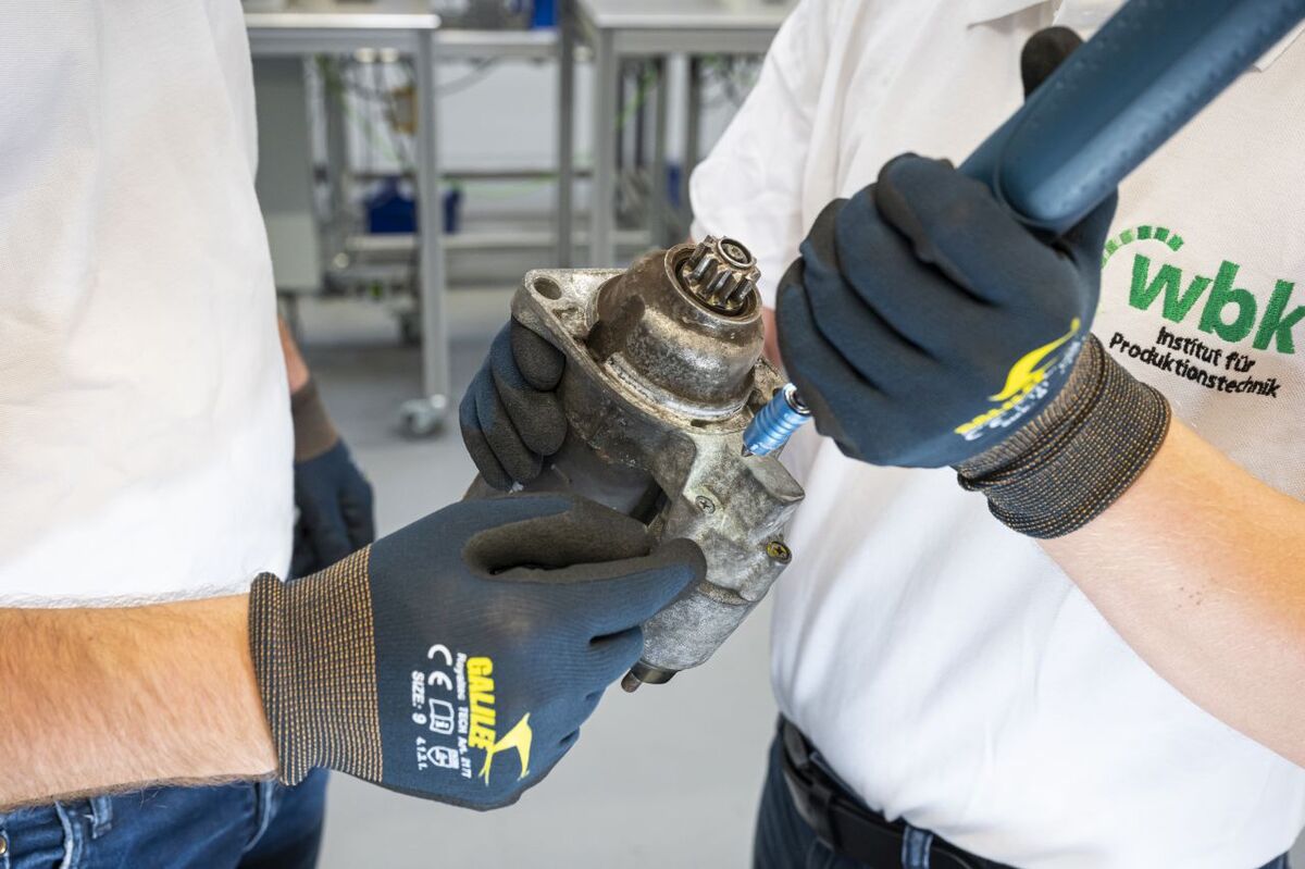 Zwei Mitarbeitende des wbk Instituts für Produktionstechnik bei der manuellen Demontage eines Motors