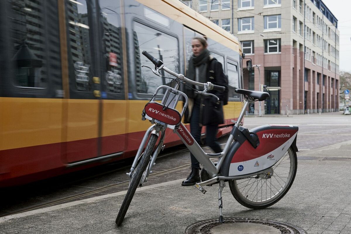 Geparktes Leihfahrrad vor einer vorbeifahrenden Straßenbahn