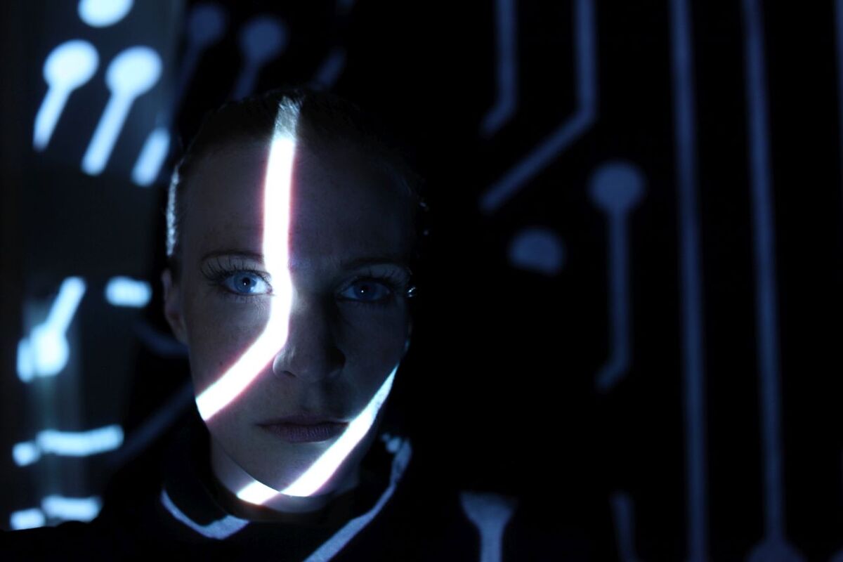 Gesicht einer Frau im Dunkeln, mit hellen Lichtstreifen beleuchtet