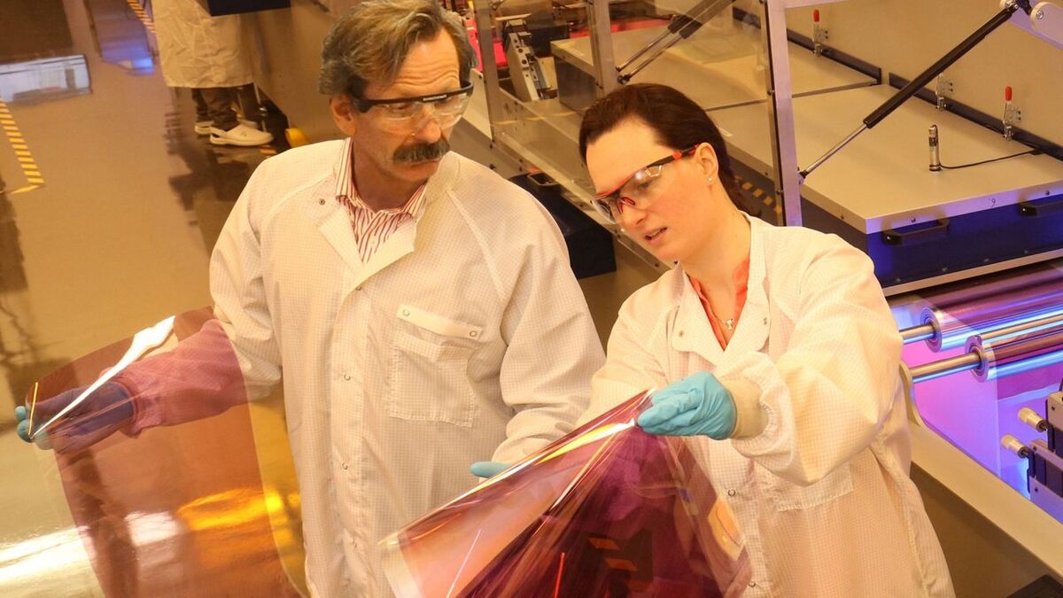 Zwei Forschende, die gedruckte Solarzellen prüfend ansehen
