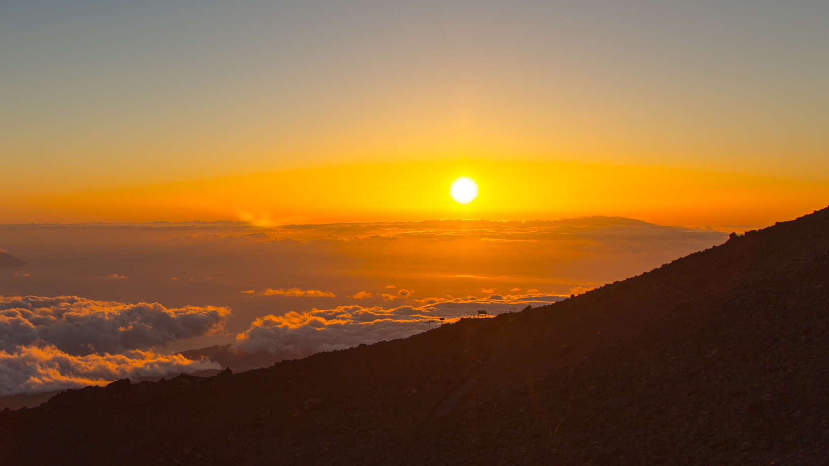 Florian Ehmele Sonnenaufgang über den Wolken mit Bergsilhouette im Vordergrund.