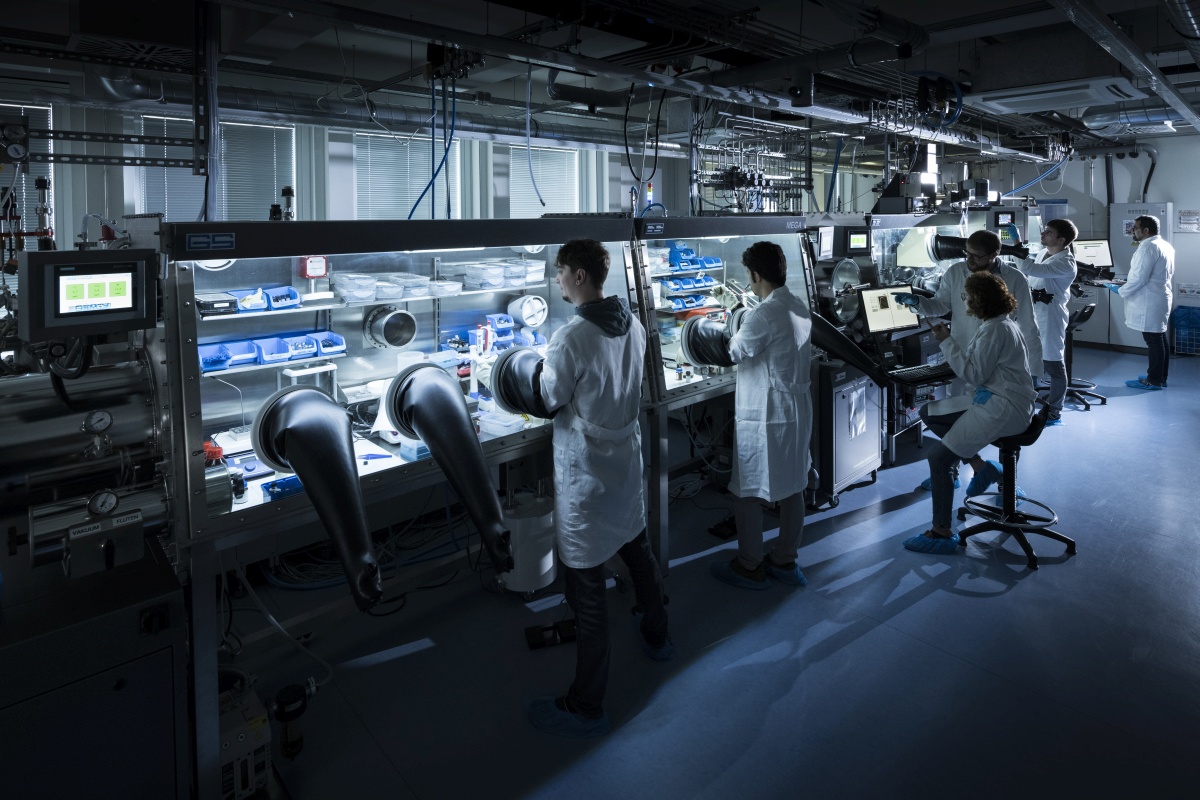 Forschende arbeiten an Gloveboxen in einem Forschungslabor.