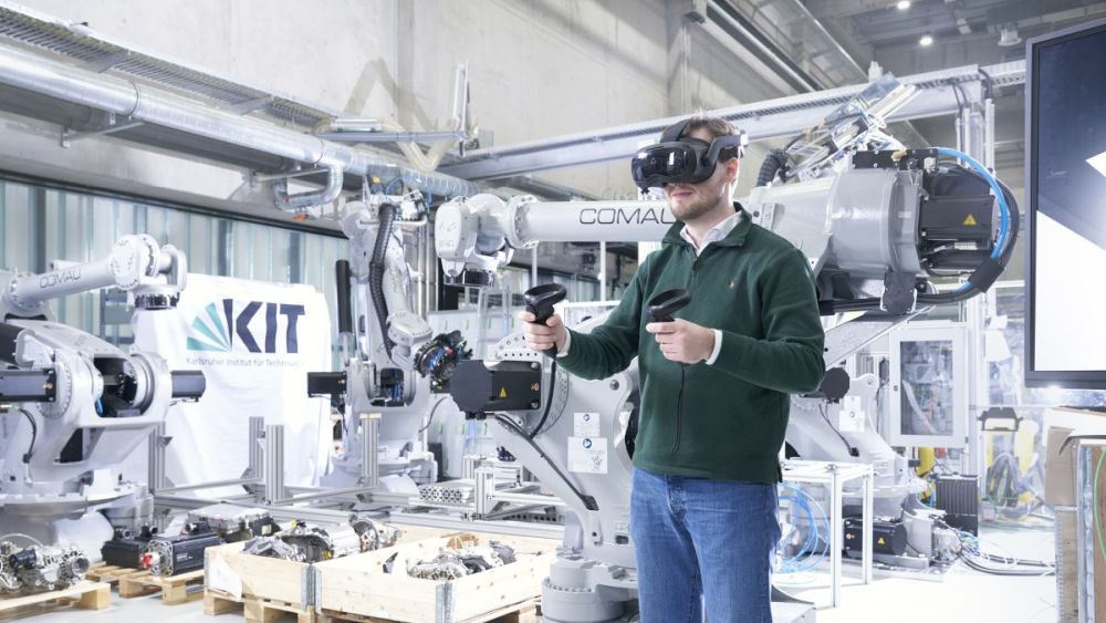 Mann steuert Industrieroboter mit VR-Controllern für die softwaregesteuerte Prozessoptimierung in der Forschungsfabrik des KIT.