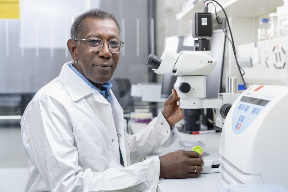 Andrew Cato sitzt im Labor vor einem Mikroskop.