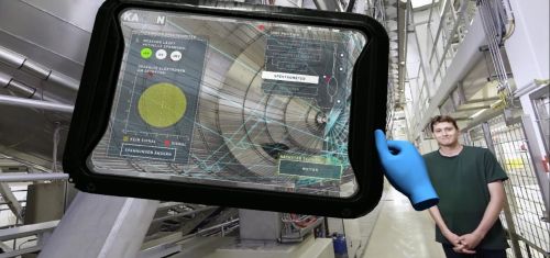 Einblick in die VR-Anwendung: Der Physiker Dr. Manuel Klein erkl&auml;rt neben dem Hauptspektrometer-Tank das KATRIN-Experiment. Mit dem virtuellen Tablet k&ouml;nnen die Benutzer und Benutzerinnen der VR-Anwendung das Experiment steuern. (Quelle: Screenshot aus der Anwendung)